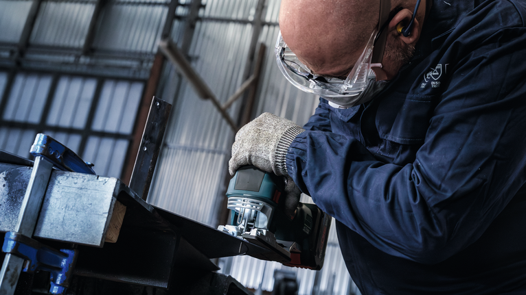 บุคคลที่สวมอุปกรณ์ความปลอดภัยเจียรขอบคานโลหะ