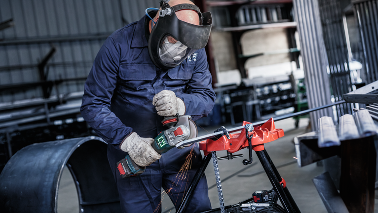 บุคคลที่สวมอุปกรณ์ด้านความปลอดภัยใช้เครื่องเจียรตัดโลหะ จึงเกิดประกายไฟขึ้น