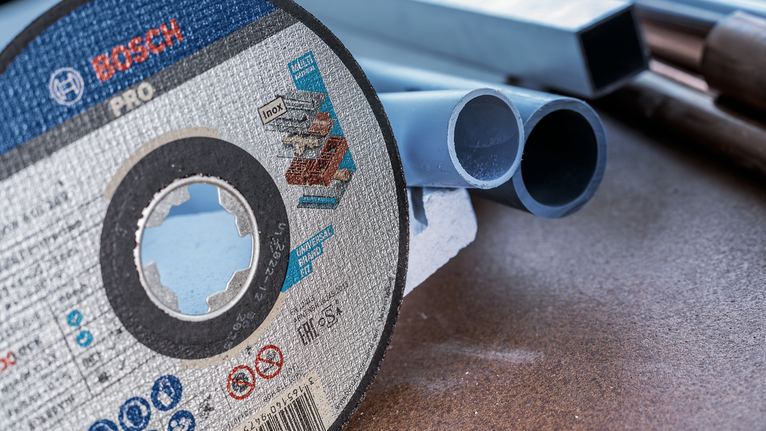 ใบตัดวางอยู่บนโต๊ะทำงานข้างท่อพลาสติกหลายท่อ