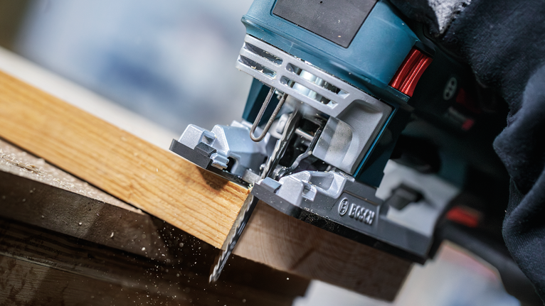 บุคคลที่สวมอุปกรณ์ความปลอดภัยใช้จิ๊กซอว์ตัดแผ่นไม้