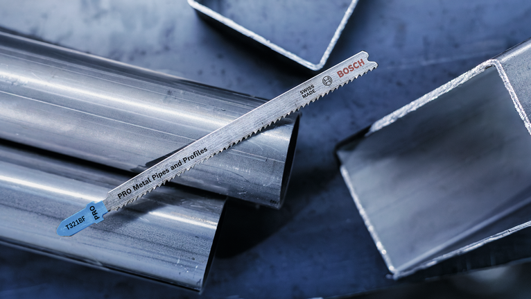 ใบเลื่อยโลหะวางอยู่บนท่อโลหะมันวาวและท่อสี่เหลี่ยม