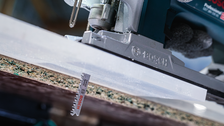 บุคคลที่สวมอุปกรณ์ความปลอดภัยกำลังตัดกระดานโดยใช้จิ๊กซอว์