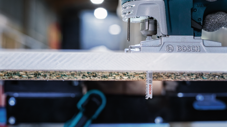 จิ๊กซอว์ไฟฟ้ากำลังตัดผ่านชิ้นไม้ลามิเนต