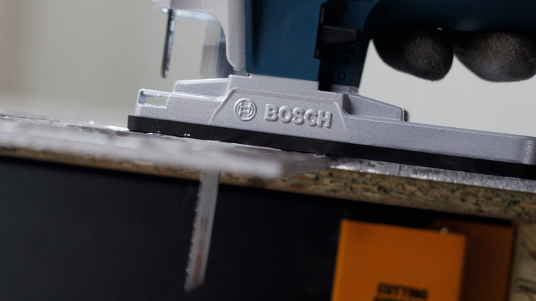 บุคคลที่สวมอุปกรณ์ความปลอดภัยกำลังนำจิ๊กซอว์ไปตัดแผ่นไม้