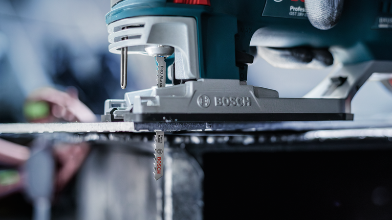 บุคคลที่สวมอุปกรณ์ความปลอดภัยกำลังนำจิ๊กซอว์ตัดผ่านแผ่นโลหะ