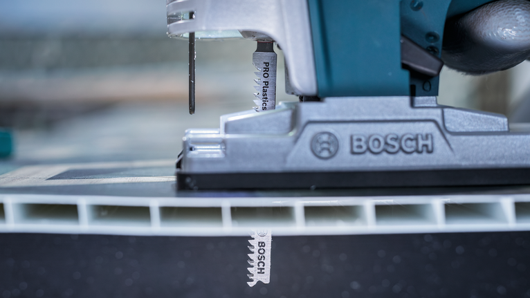 จิ๊กซอว์ตัดผ่านแผงพลาสติกหนาในฉากเวิร์กช็อปแบบใกล้ชิด