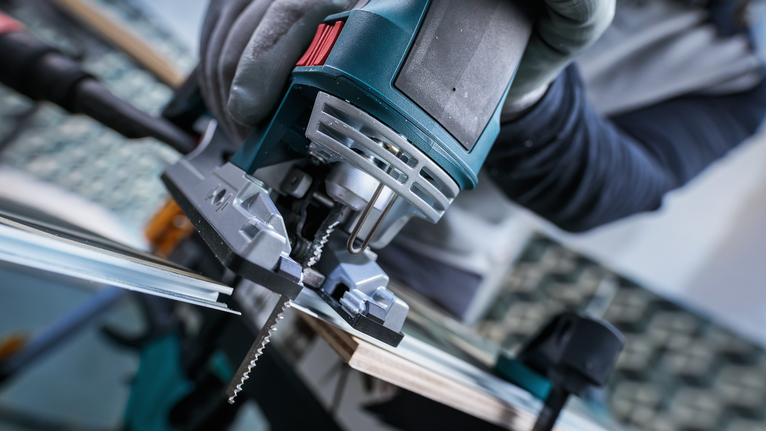 บุคคลที่สวมอุปกรณ์ความปลอดภัยกำลังตัดไม้ด้วยจิ๊กซอว์