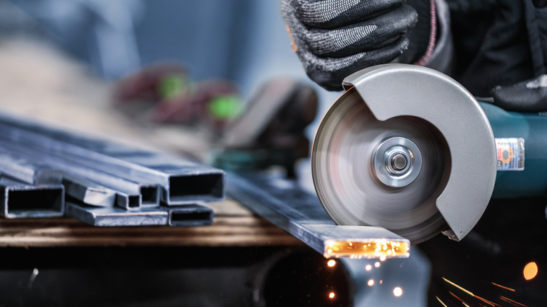 บุคคลที่สวมอุปกรณ์ความปลอดภัยตัดโลหะด้วยเครื่องเจียร ทำให้เกิดประกายไฟ