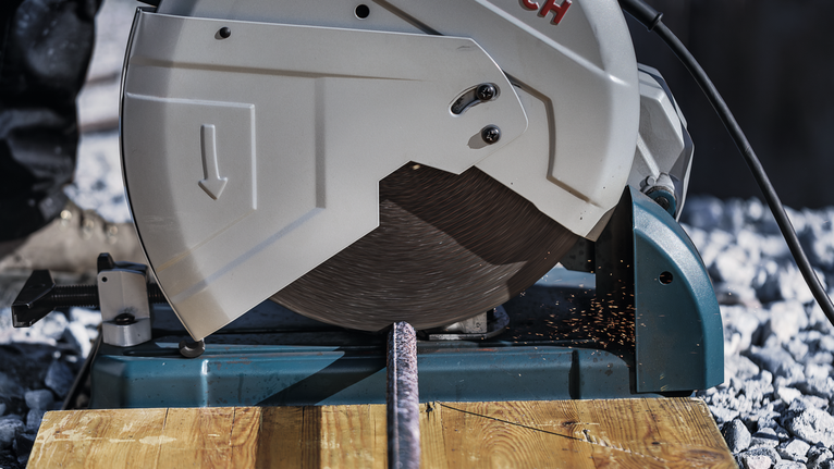 ใบเลื่อยตัดโลหะกำลังตัดผ่านเหล็กเส้น ทำให้เกิดประกายไฟบนพื้นผิวไม้