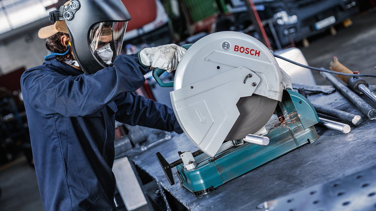 บุคคลที่สวมอุปกรณ์ความปลอดภัยกำลังตัดท่อโลหะด้วยเลื่อยวงเดือนแบบตั้งพื้น