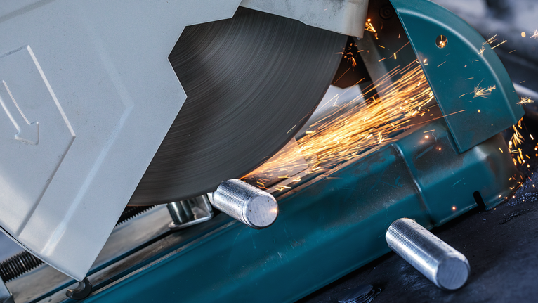 เลื่อยตัดโลหะกำลังตัดผ่านแท่งเหล็กและมีประกายไฟพุ่งออกมา