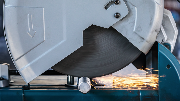 ใบเลื่อยตัดโลหะกำลังตัดผ่านท่อและมีประกายไฟสว่างพุ่งออกมา