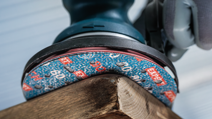 บุคคลที่สวมอุปกรณ์ความปลอดภัยกำลังขัดมุมแผ่นไม้