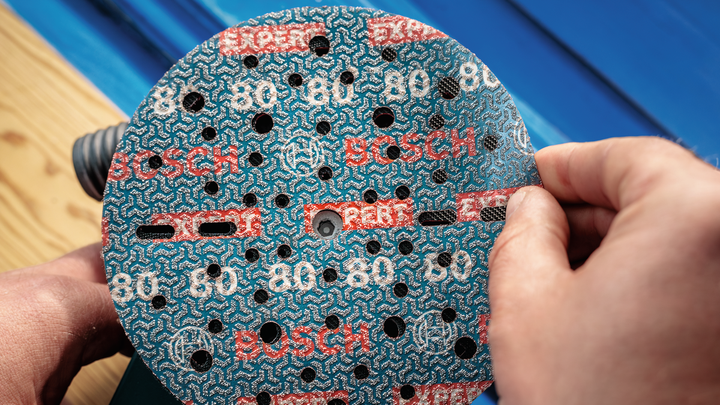 คนกำลังติดแผ่นขัดเข้ากับเครื่องขัดไฟฟ้า