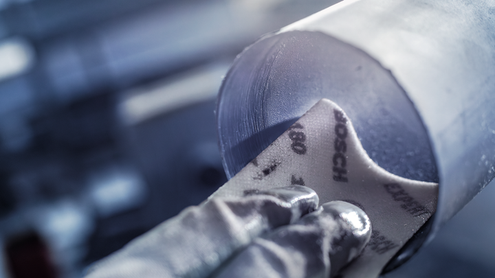 บุคคลที่สวมอุปกรณ์ด้านความปลอดภัยกำลังขัดด้านในของท่อโลหะ