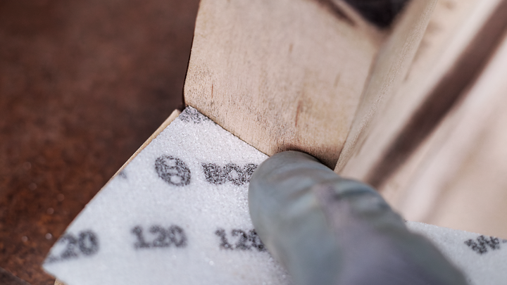 บุคคลที่สวมอุปกรณ์ความปลอดภัยกำลังขัดมุมพื้นผิวไม้