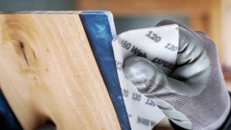 บุคคลที่สวมอุปกรณ์ความปลอดภัยกำลังขัดพื้นไม้