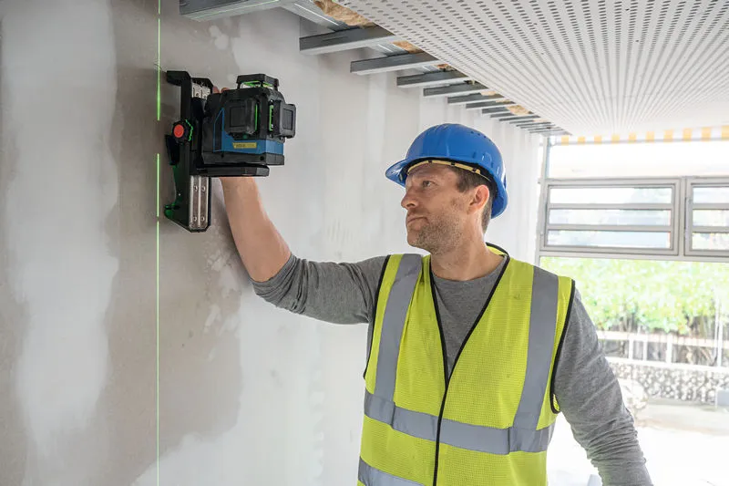 บุคคลที่สวมอุปกรณ์ด้านความปลอดภัยกำลังวางเครื่องมือวัดระดับเลเซอร์บนผนัง.