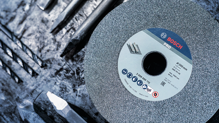 ล้อเจียรวางอยู่บนโต๊ะทำงานข้างดอกสว่านโลหะหลายอัน