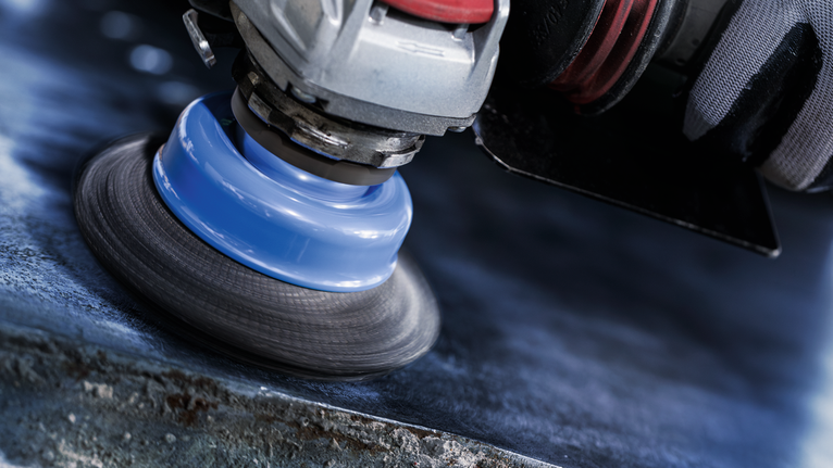 บุคคลที่สวมอุปกรณ์ด้านความปลอดภัยขัดพื้นผิวโลหะด้วยเครื่องมือหมุน