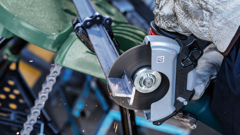 บุคคลที่สวมอุปกรณ์ความปลอดภัยกำลังตัดท่อโลหะด้วยเลื่อยวงเดือน