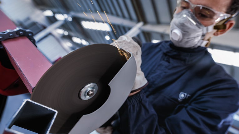 บุคคลที่สวมอุปกรณ์ความปลอดภัยตัดโลหะด้วยเครื่องเจียรแบบมุมหมุน