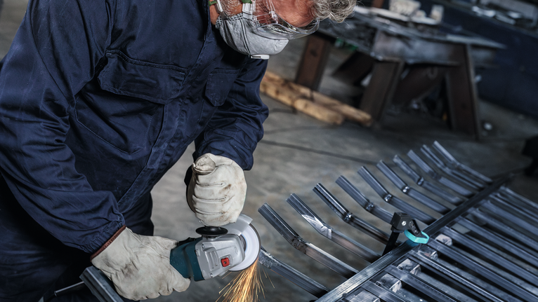 บุคคลที่สวมอุปกรณ์นิรภัยบดแท่งโลหะ มีประกายไฟกระเด็นออกมา