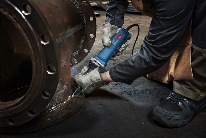 ผู้ที่สวมอุปกรณ์ด้านความปลอดภัยจะใช้เครื่องเจียรตรงกับหน้าแปลนโลหะ.