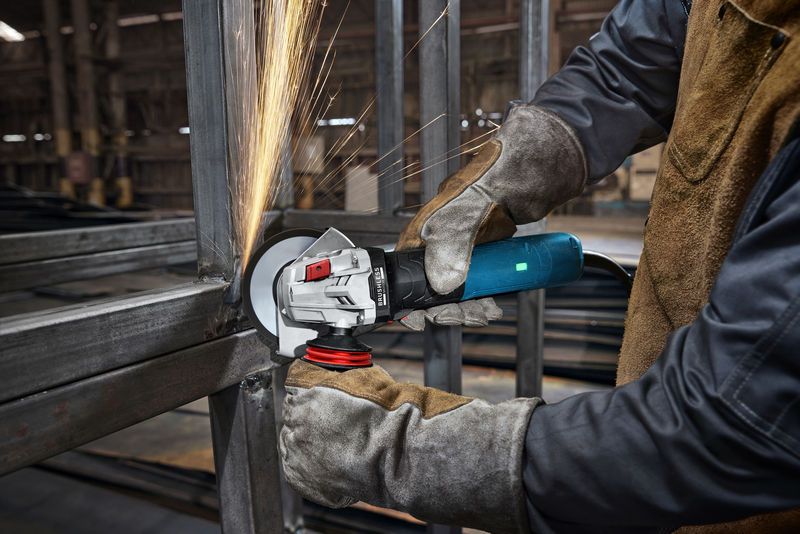 บุคคลที่สวมอุปกรณ์ด้านความปลอดภัยกำลังบดโลหะ ทำให้เกิดประกายไฟในสถานประกอบการอุตสาหกรรม.