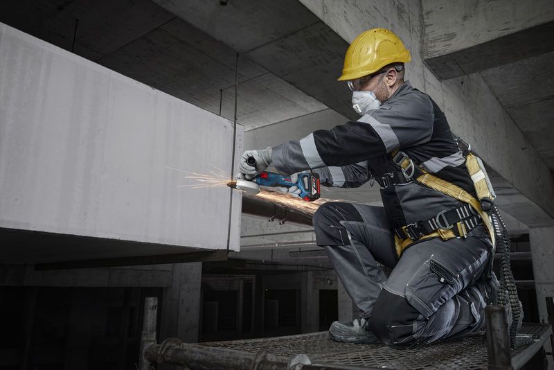 บุคคลที่สวมอุปกรณ์ความปลอดภัยกำลังบดคอนกรีตด้วยเครื่องมือไฟฟ้าในไซต์ก่อสร้าง.