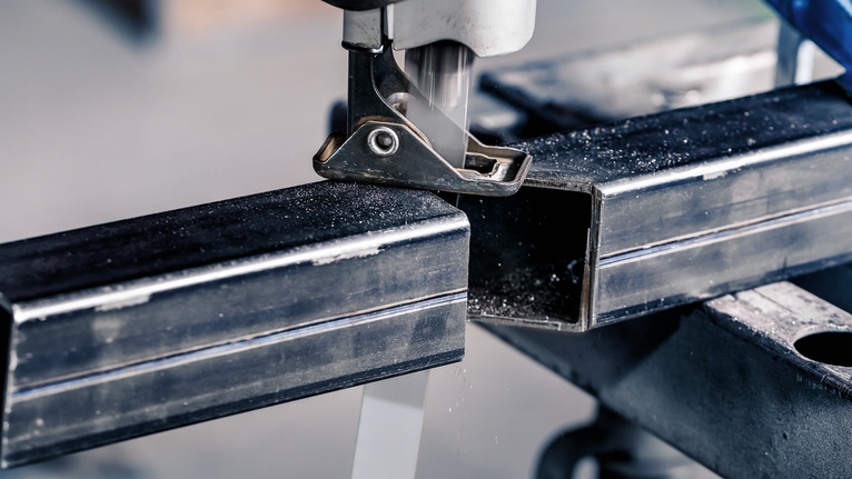 จิ๊กซอว์ตัดผ่านท่อสี่เหลี่ยมโลหะบนโต๊ะทำงาน