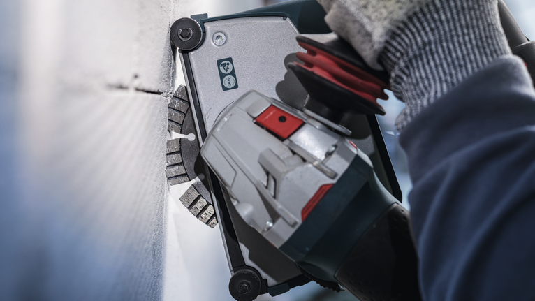 บุคคลที่สวมอุปกรณ์ความปลอดภัยใช้เครื่องมือไฟฟ้าตัดเข้าไปในผนัง