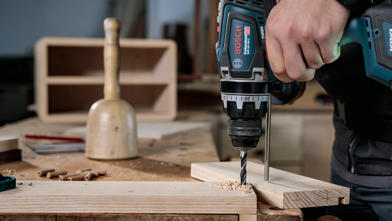 คนกำลังเจาะรูบนแผ่นไม้ในโรงงาน