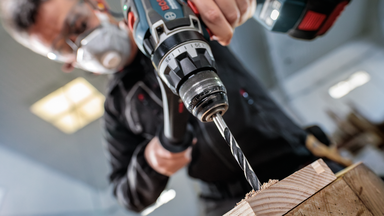 คนสวมอุปกรณ์นิรภัยกำลังเจาะไม้