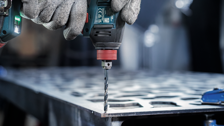 ผู้ที่สวมอุปกรณ์เซฟตี้กำลังเจาะแผ่นโลหะ