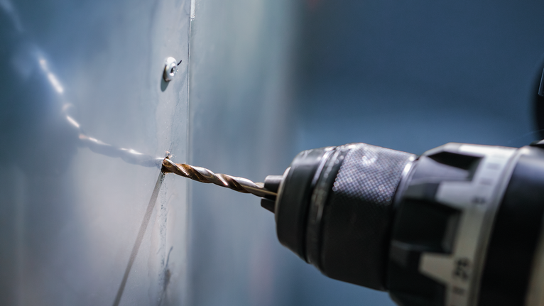 สว่านไฟฟ้ากำลังเจาะรูบนแผ่นโลหะ