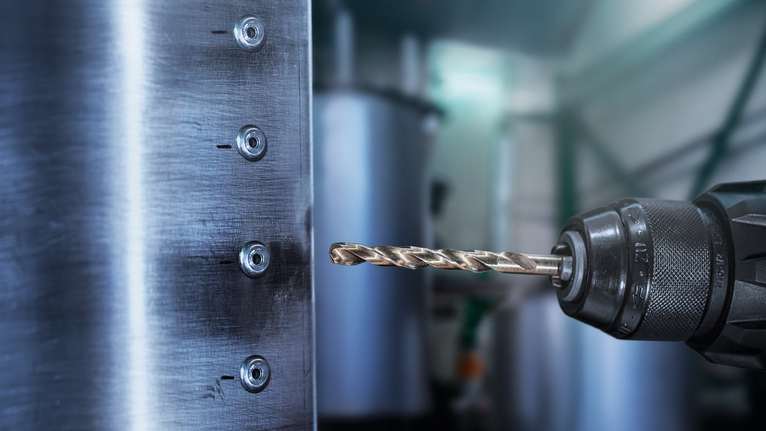 สว่านไฟฟ้ากำลังเจาะรูบนแผงโลหะ