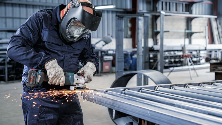 บุคคลที่สวมอุปกรณ์ความปลอดภัยทำการเจียรโลหะ ทำให้เกิดประกายไฟ