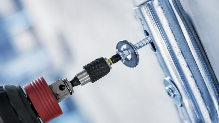 เครื่องมือไฟฟ้ากำลังขันสกรูเข้าไปในบานพับโลหะ