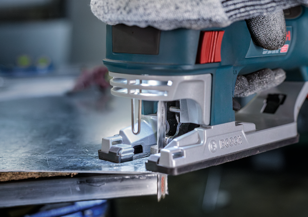 ผู้ที่สวมอุปกรณ์ความปลอดภัยใช้จิ๊กซอว์ตัดแผ่นโลหะ