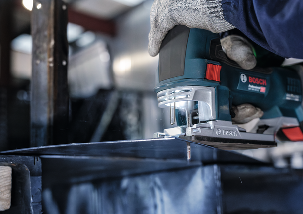 บุคคลที่สวมอุปกรณ์ความปลอดภัยกำลังตัดโลหะด้วยจิ๊กซอว์ในสถานประกอบการอุตสาหกรรม