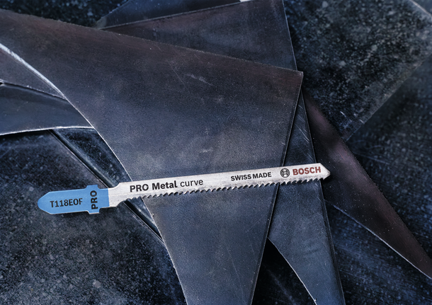 ใบเลื่อยจิ๊กซอว์โลหะวางอยู่บนแผ่นโลหะที่วางซ้อนกัน