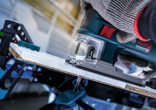 บุคคลที่สวมอุปกรณ์ความปลอดภัยใช้เลื่อยจิ๊กซอว์ตัดแผ่นไม้