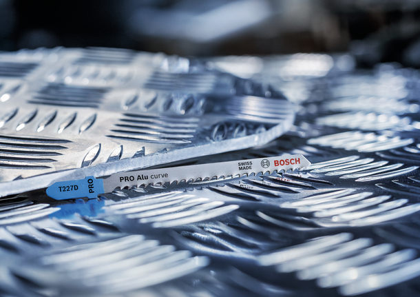 ใบเลื่อยจิ๊กซอว์โลหะวางอยู่บนแผ่นอลูมิเนียมที่มีพื้นผิวสัมผัส