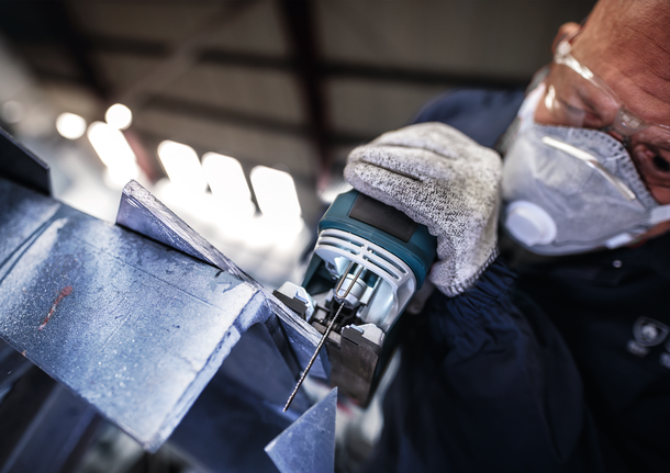 ผู้ที่สวมอุปกรณ์ความปลอดภัยใช้จิ๊กซอว์ตัดแผ่นโลหะ