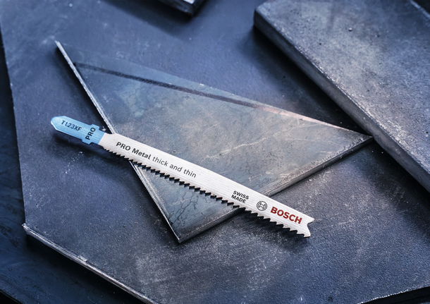 ใบเลื่อยจิ๊กซอว์โลหะวางอยู่บนแผ่นโลหะสีเข้ม