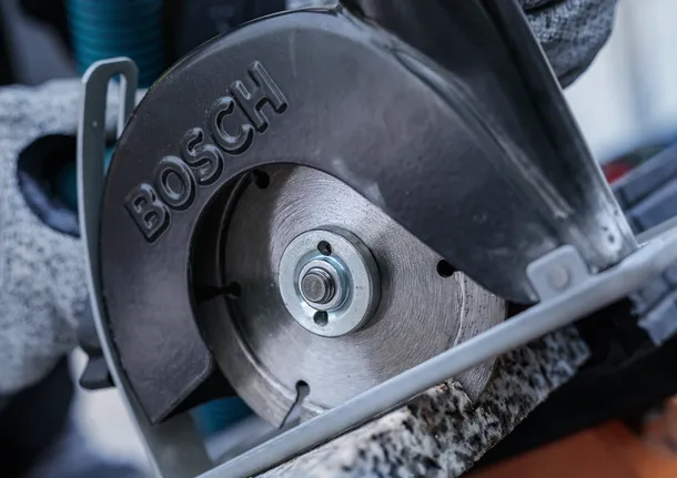 บุคคลที่สวมอุปกรณ์ความปลอดภัยกำลังตัดหินด้วยเลื่อยวงเดือน