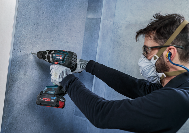 ผู้ที่สวมอุปกรณ์ป้องกันความปลอดภัยกำลังเจาะเข้าไปในผนัง