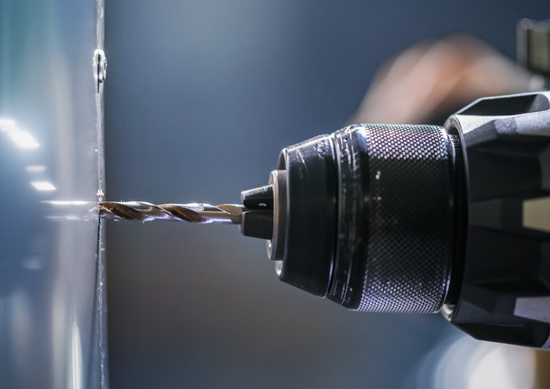 สว่านไฟฟ้ากำลังเจาะรูบนพื้นผิวโลหะ