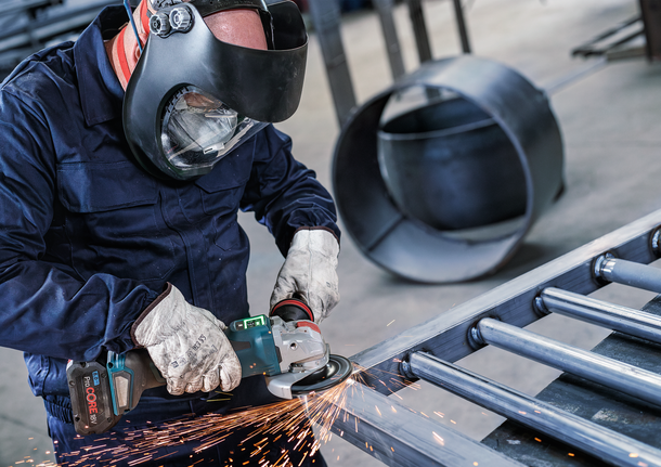 บุคคลที่สวมอุปกรณ์ความปลอดภัยทำการบดโลหะ ทำให้เกิดประกายไฟ